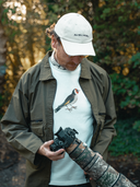 Model holding camera wearing white t-shirt with goldfinch graphic print on chest